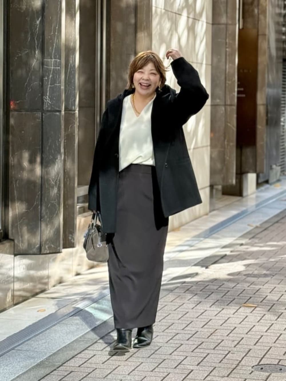 ホワイト系のニット/セーター、ブラック系のスカート、ゴールド系のネックレスを着用したレディースの冬コーディネートの6枚目の写真