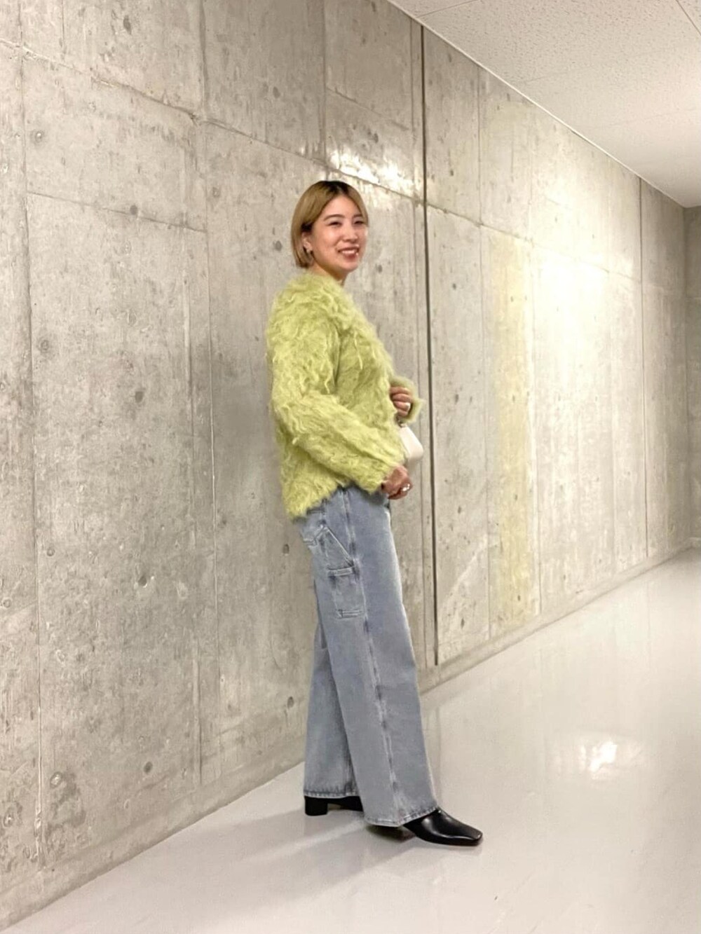 グリーン系のニット/セーター、ブルー系のデニムパンツを着用したレディースの冬コーディネートの3枚目の写真