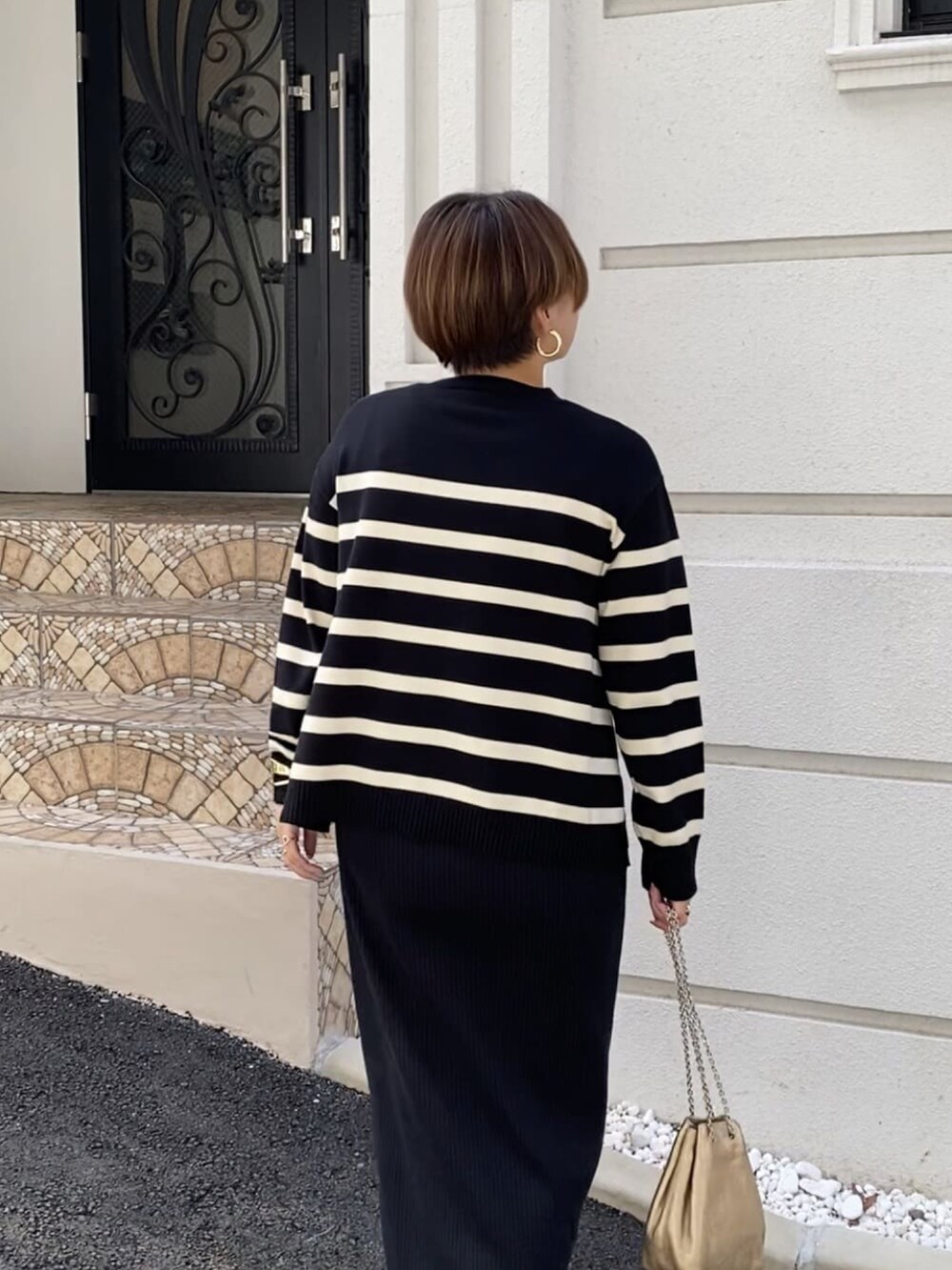 ブラック系のニット/セーター、ブラック系のスカート、ブラック系のブーツを着用したレディースの秋コーディネートの4枚目の写真