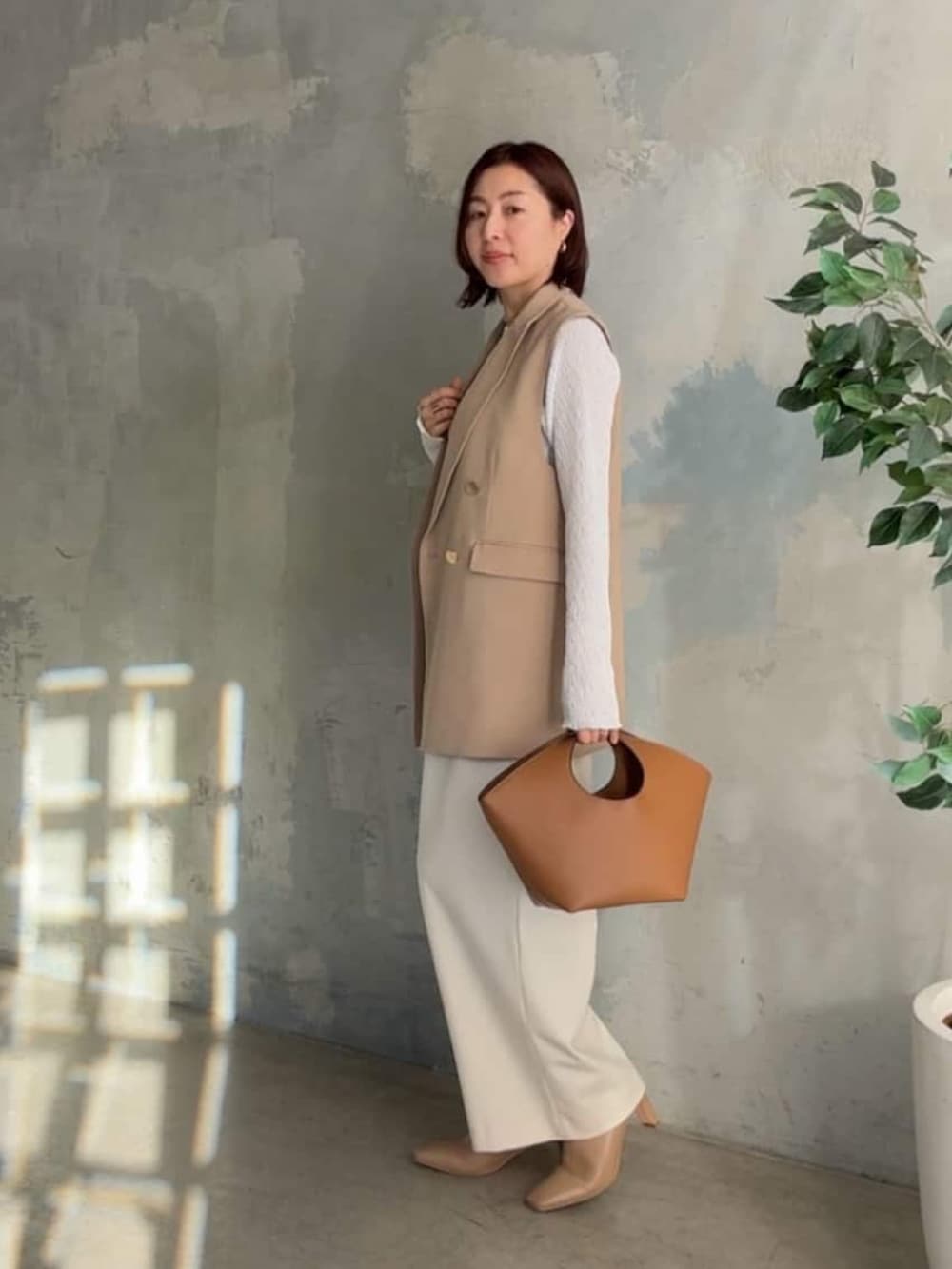 ホワイト系のTシャツ/カットソー、ベージュ系のベスト、イエロー系のハンドバッグを着用したレディースの冬コーディネートの2枚目の写真