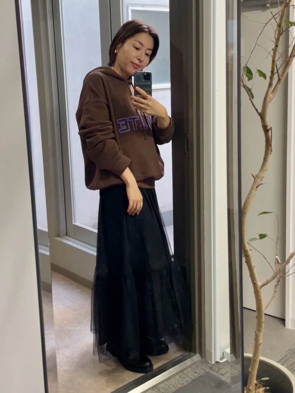 ブラック系のスカート、ブラウン系のパーカーを着用したレディースの秋コーディネートの2枚目の写真