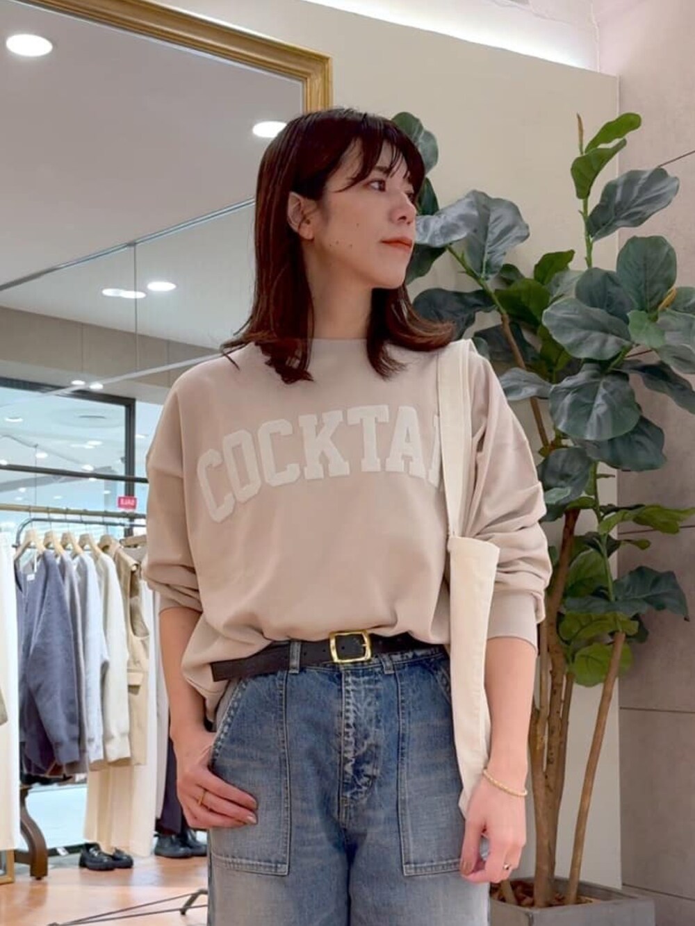 ベージュ系のスウェット、ホワイト系のトートバッグ、ブルー系のデニムパンツを着用したレディースの冬コーディネートの5枚目の写真