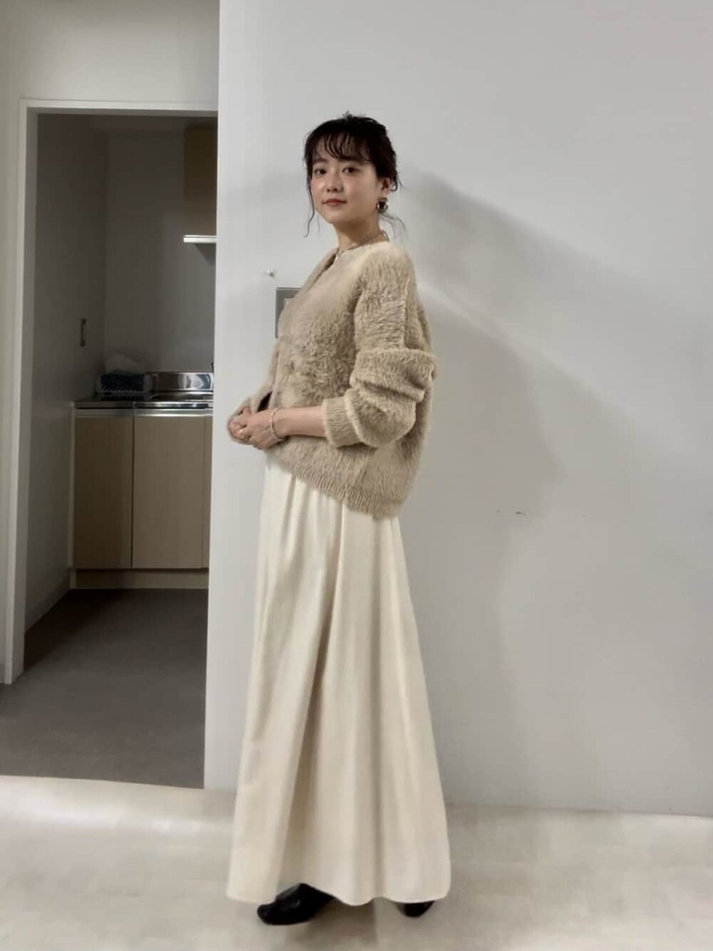 グレー系のカーディガン/ボレロ、ブラウン系のスカート、ブラック系のブーツを着用したレディースの冬コーディネートの2枚目の写真