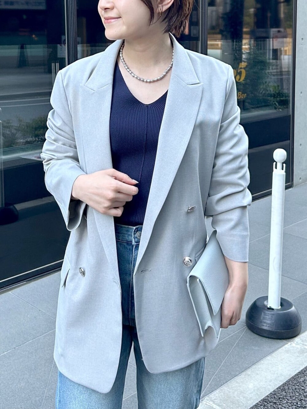 ブルー系のニット/セーター、グレー系のテーラードジャケット、ブルー系のショルダーバッグを着用したレディースの春コーディネートの4枚目の写真