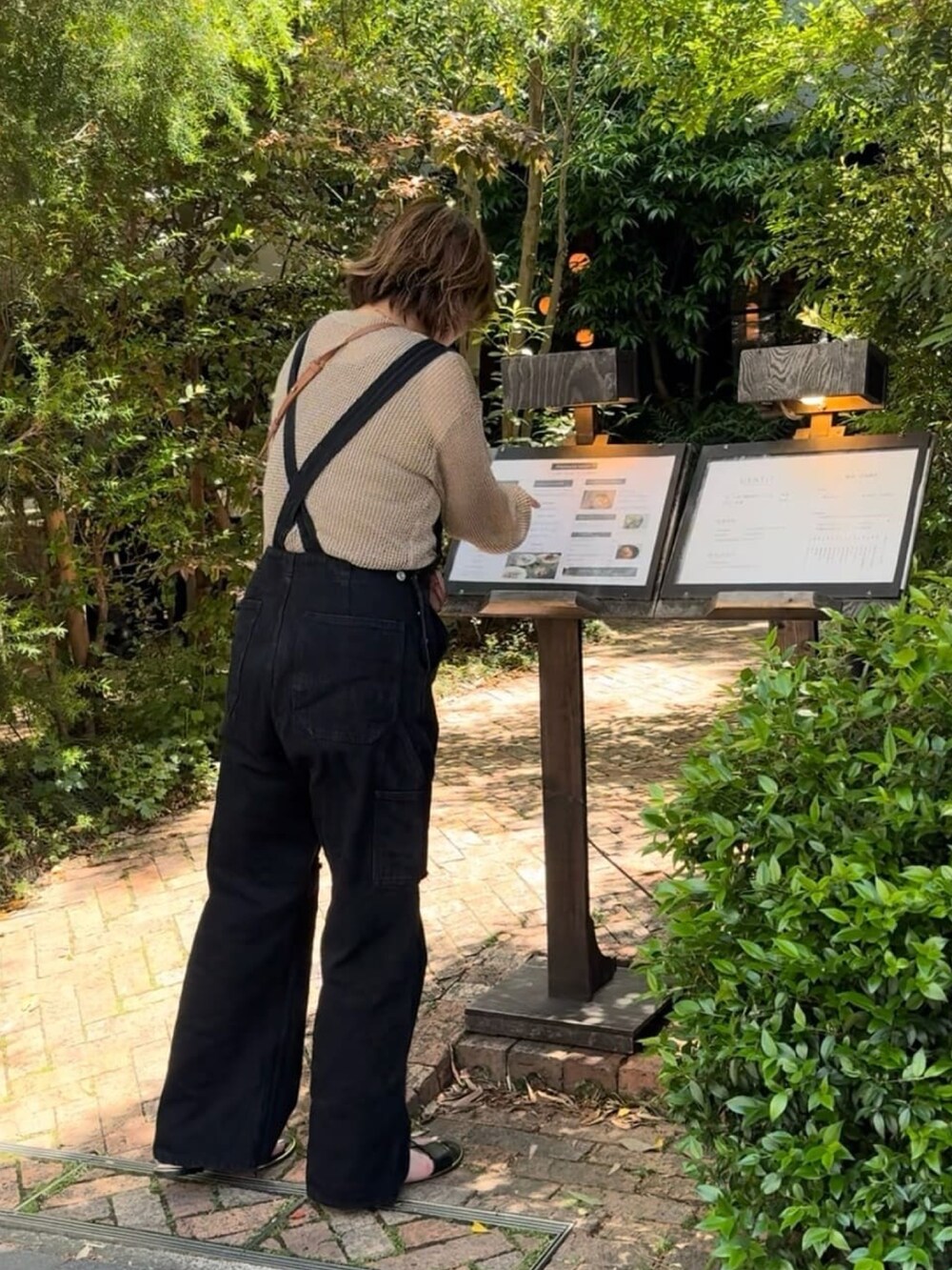 ブラック系のサロペット/オーバーオール、ブラウン系のニット/セーターを着用したレディースの春コーディネートの4枚目の写真