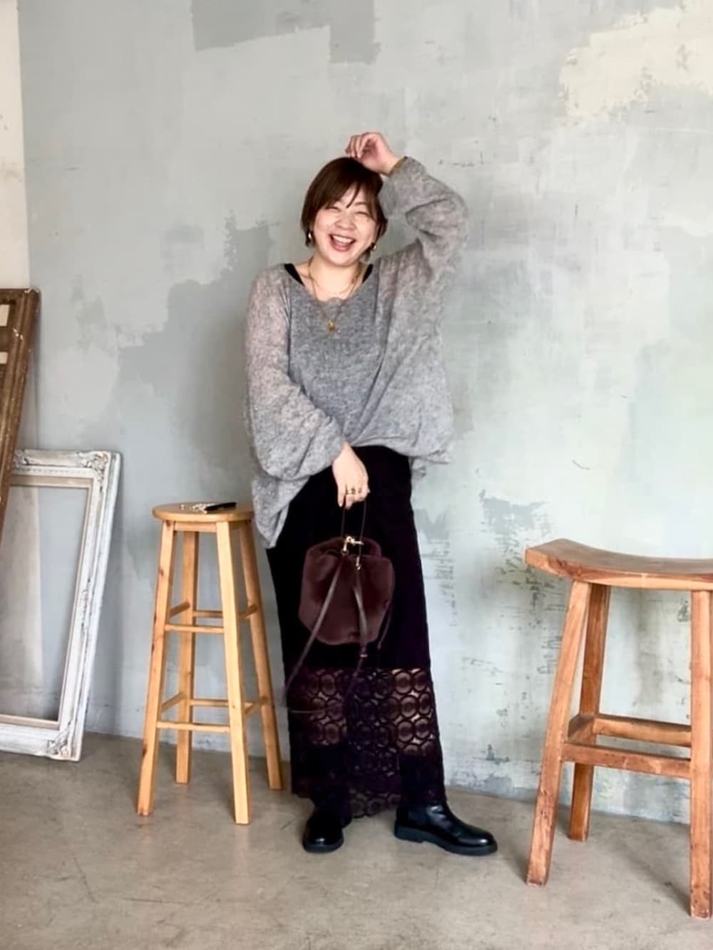 グレー系のニット/セーター、ブラウン系のハンドバッグ、ブラック系のスカートを着用したレディースの夏コーディネートの2枚目の写真