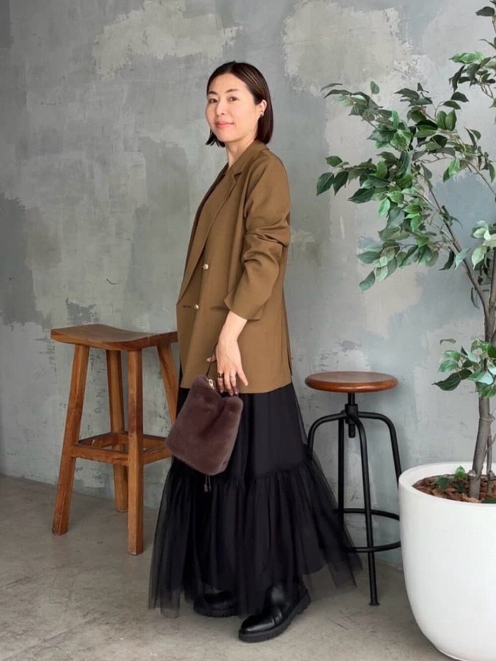 ブラウン系のテーラードジャケット、ブラウン系のTシャツ/カットソー、ブラック系のスカートを着用したレディースの秋コーディネートの2枚目の写真