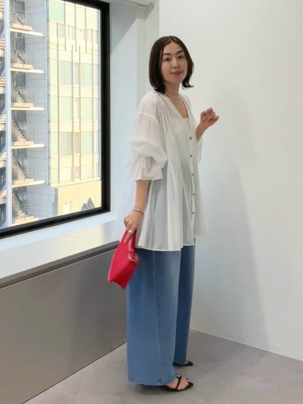 ブラック系のサンダル、ブルー系のデニムパンツ、レッド系のハンドバッグを着用したレディースの春コーディネートの2枚目の写真