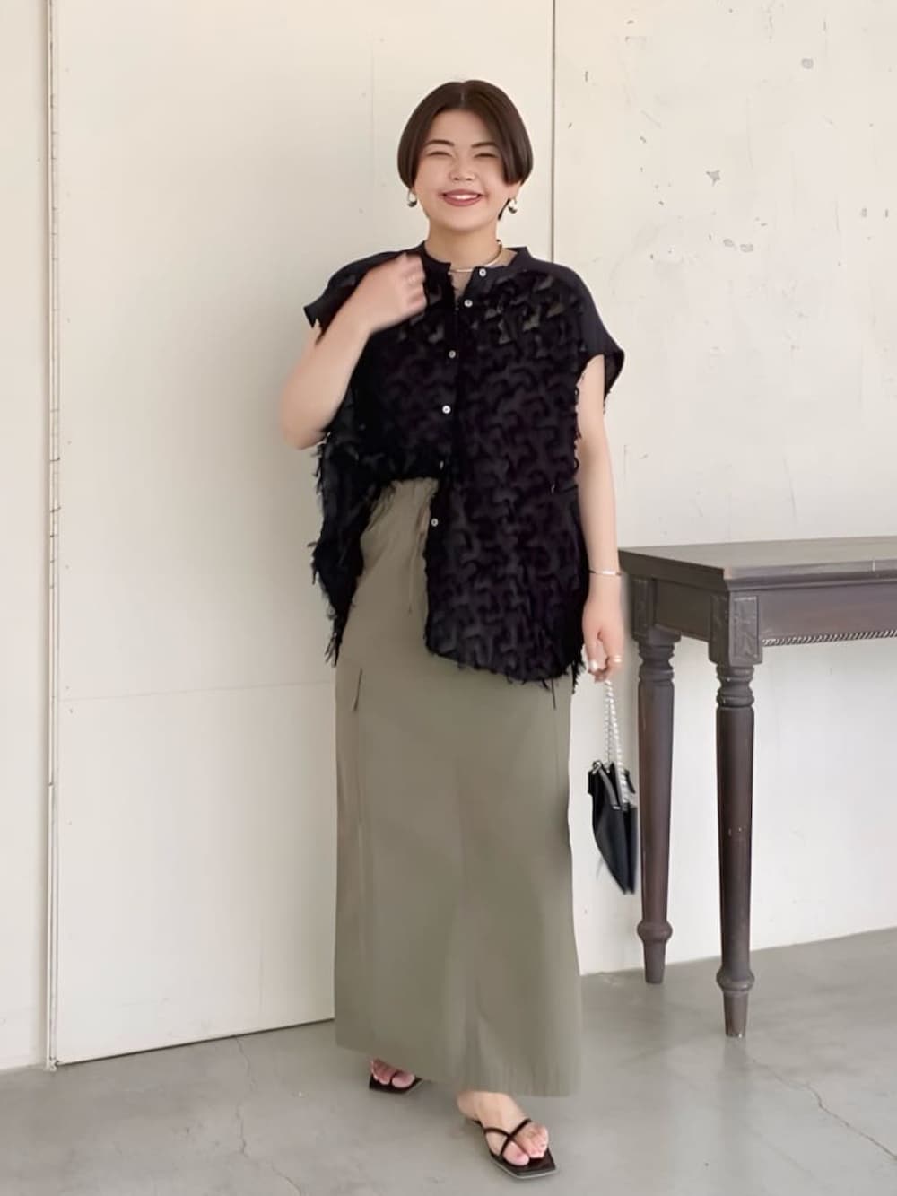 ブラック系のシャツ/ブラウス、ブラック系のショルダーバッグ、グリーン系のスカートを着用したレディースの夏コーディネートの2枚目の写真