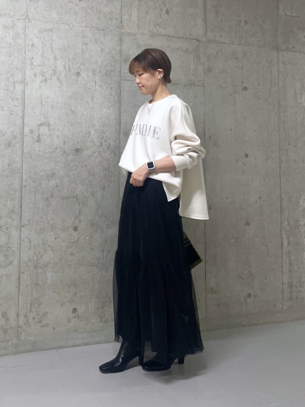 ホワイト系のTシャツ/カットソー、ブラック系のスカート、ブラック系のブーツを着用したレディースの秋コーディネートの2枚目の写真