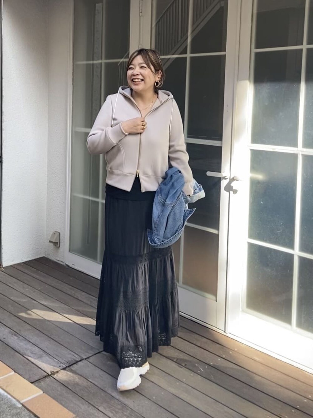ベージュ系のパーカー、ブラック系のスカートを着用したレディースの秋コーディネートの3枚目の写真