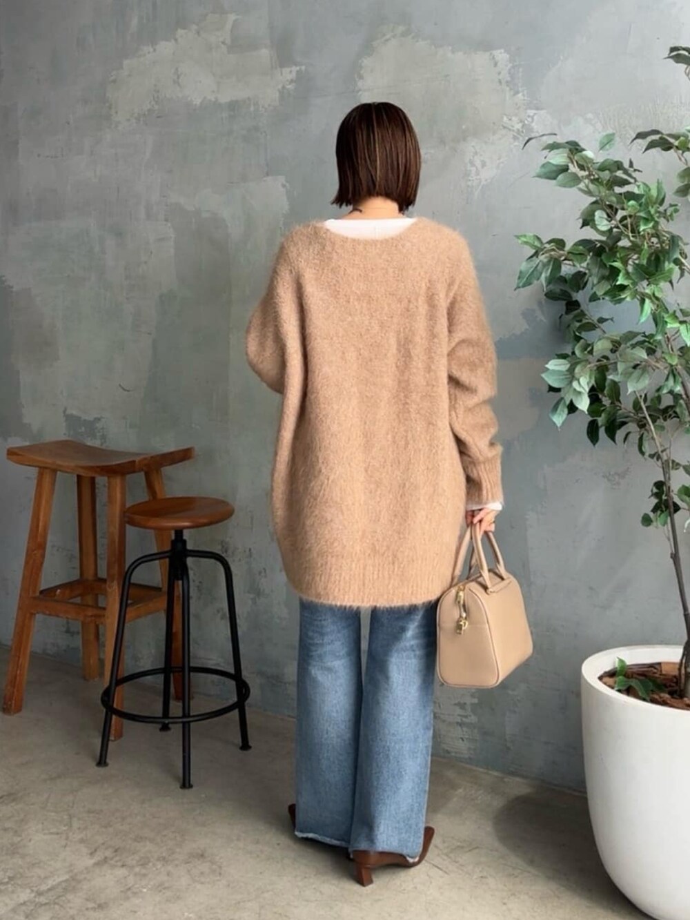 イエロー系のニット/セーター、ブルー系のデニムパンツ、ベージュ系のボストンバッグを着用したレディースの秋コーディネートの3枚目の写真