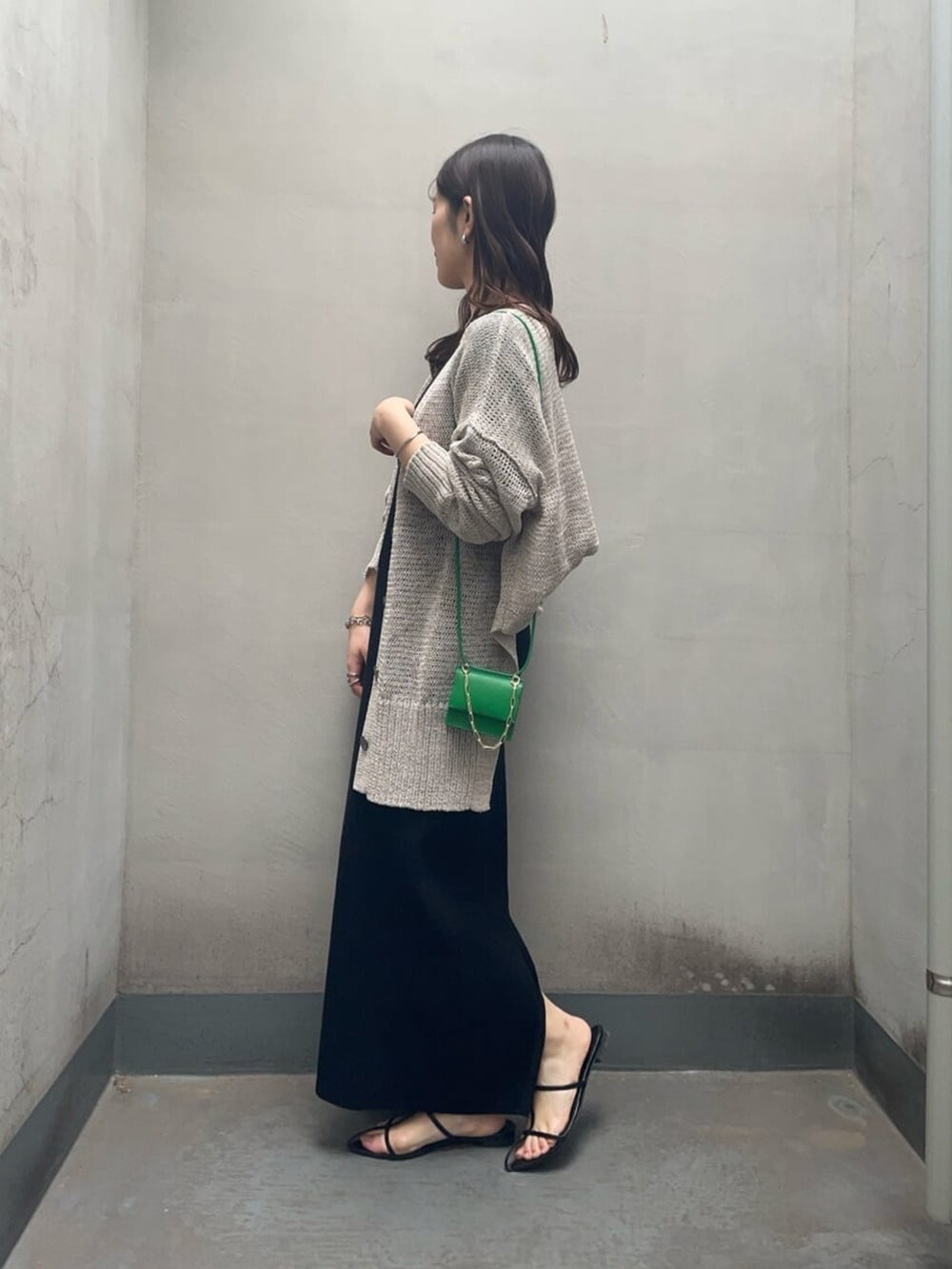ブラック系のワンピース、グレー系のカーディガン/ボレロ、ブラック系のサンダルを着用したレディースの春コーディネートの2枚目の写真