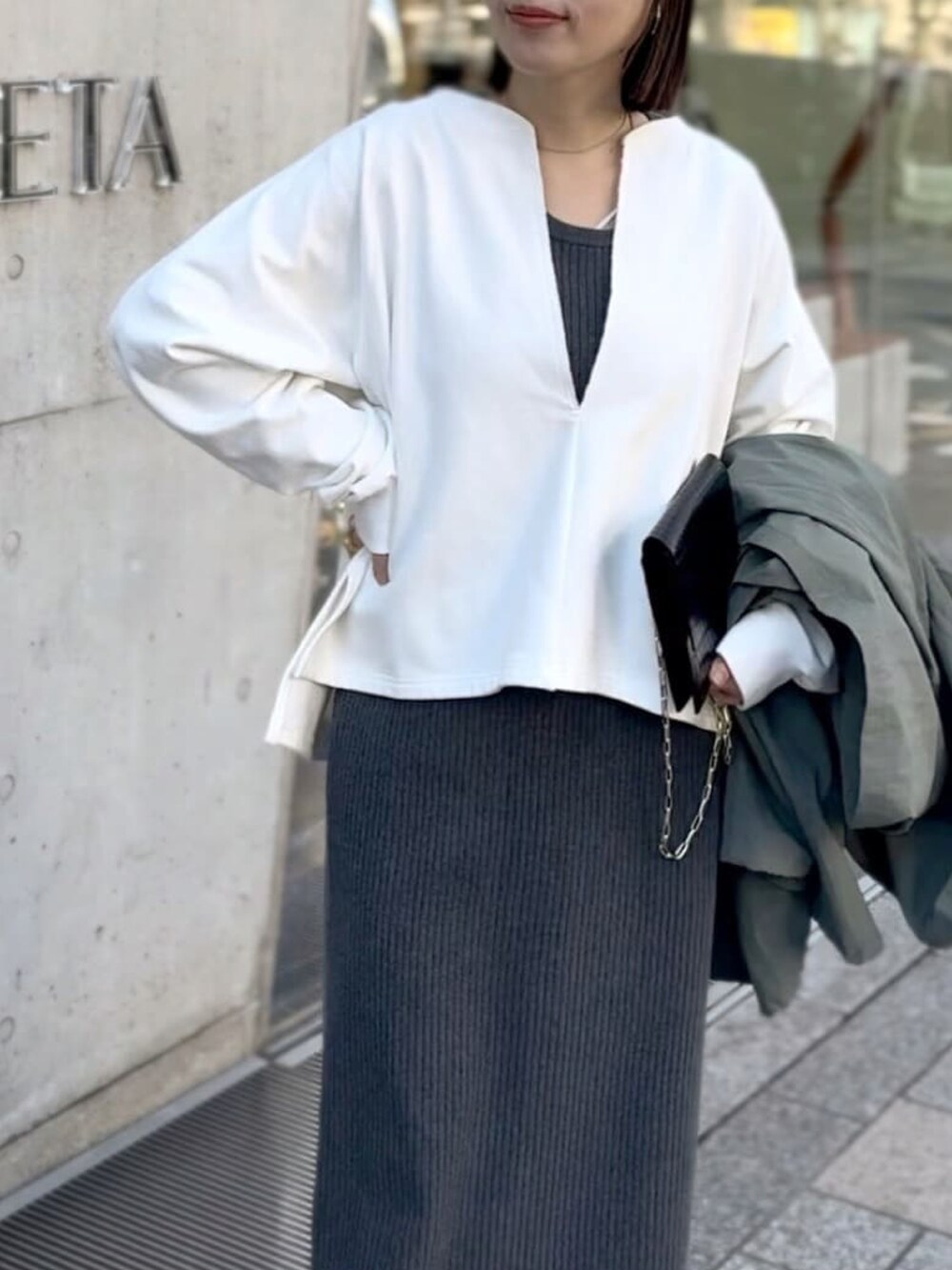 グレー系のワンピース、グリーン系のマウンテンパーカー、ブラック系のブーツを着用したレディースの冬コーディネートの5枚目の写真