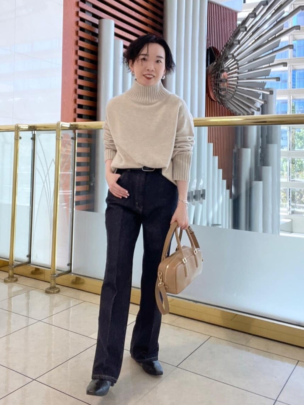 ベージュ系のニット/セーター、ブルー系のデニムパンツ、イエロー系のノーカラーコートを着用したレディースの秋コーディネートの2枚目の写真