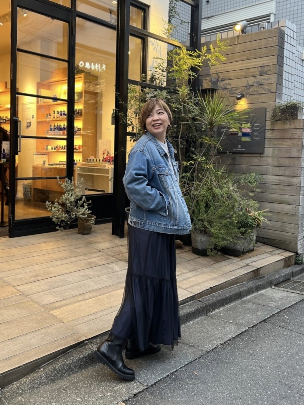 ブルー系のデニムジャケット、グレー系のニット/セーター、ブラック系のスカートを着用したレディースの春コーディネートの3枚目の写真