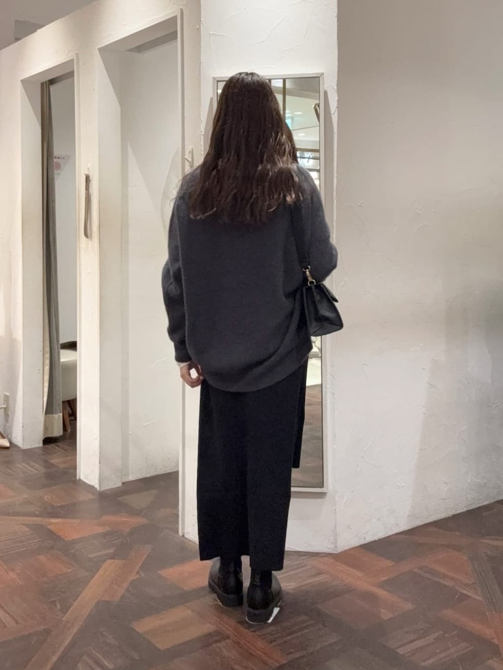 グレー系のニット/セーター、ホワイト系のTシャツ/カットソー、ブラック系のスカートを着用したレディースの冬コーディネートの2枚目の写真