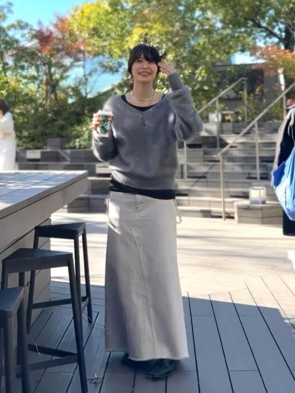 グレー系のニット/セーター、グレー系のデニムスカート、ブラック系のTシャツ/カットソーを着用したレディースの冬コーディネートの2枚目の写真