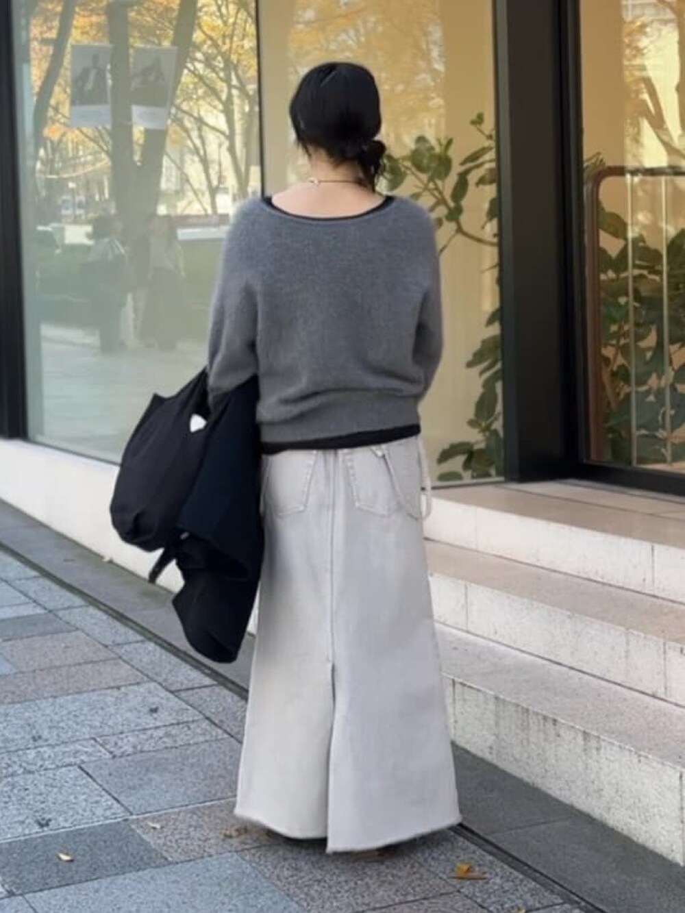 グレー系のニット/セーター、グレー系のデニムスカート、ブラック系のTシャツ/カットソーを着用したレディースの冬コーディネートの4枚目の写真