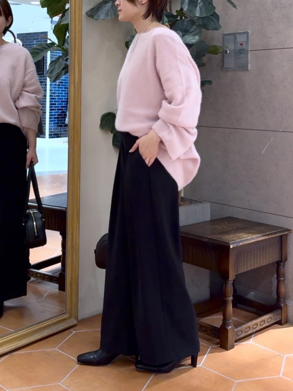 ピンク系のニット/セーター、ブラック系のスラックス、ブラック系のショルダーバッグを着用したレディースの冬コーディネートの2枚目の写真