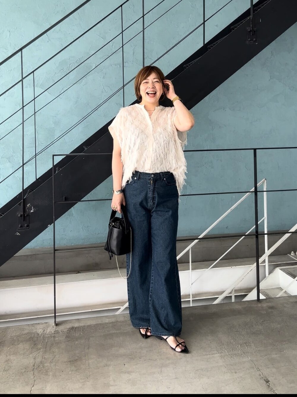 ホワイト系のシャツ/ブラウス、ブルー系のデニムパンツ、ブラック系のハンドバッグを着用したレディースの夏コーディネートの2枚目の写真