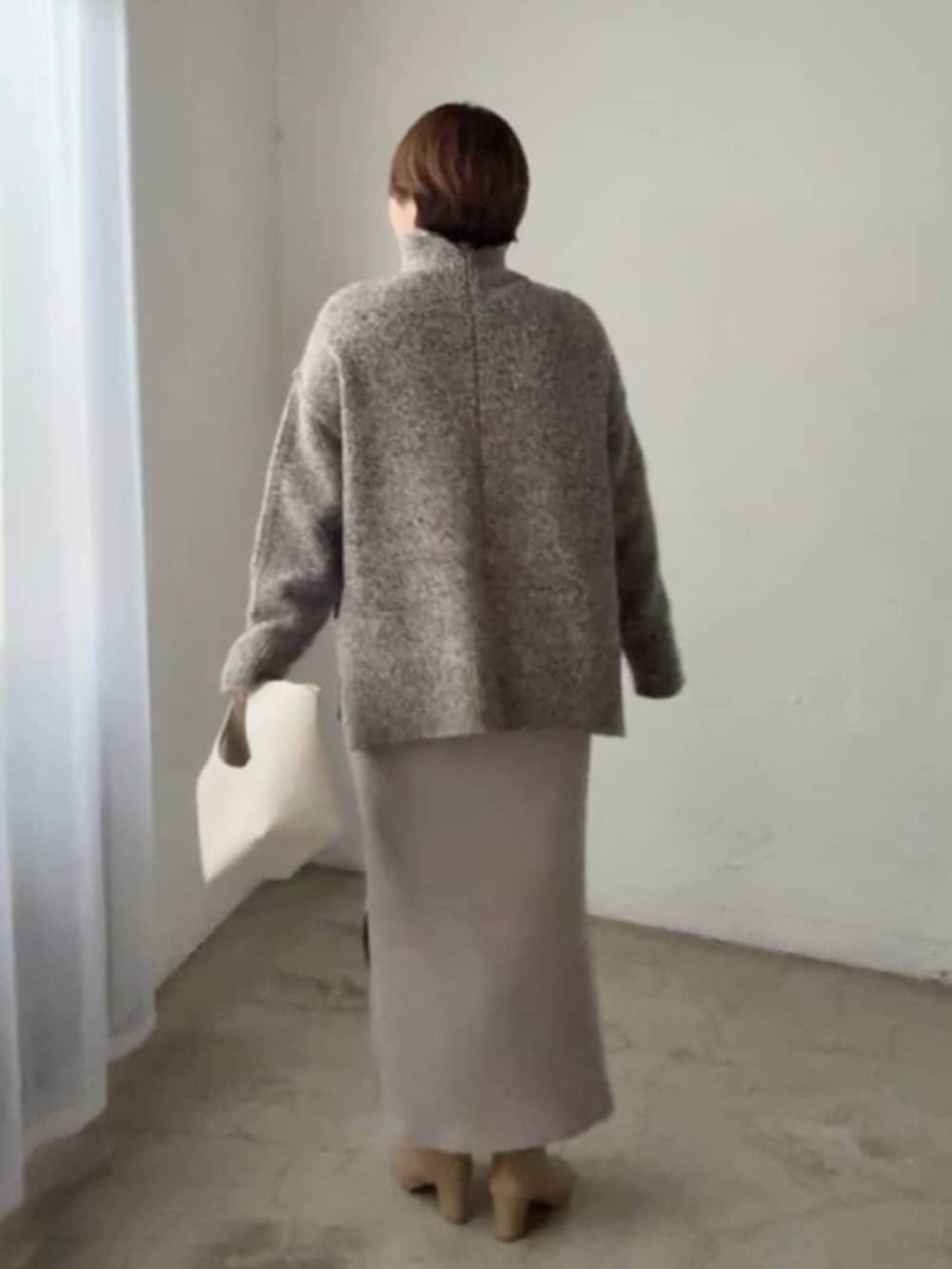 ホワイト系のハンドバッグ、ブラウン系のニット/セーター、ベージュ系のワンピースを着用したレディースの秋コーディネートの3枚目の写真