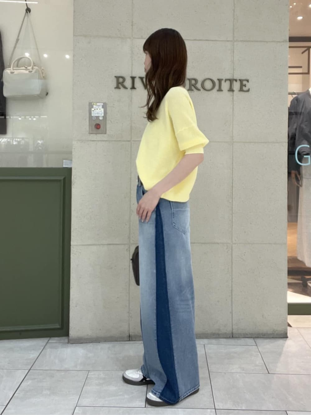 ブラウン系のボストンバッグ、イエロー系のニット/セーター、ブルー系のデニムパンツを着用したレディースの春コーディネートの2枚目の写真