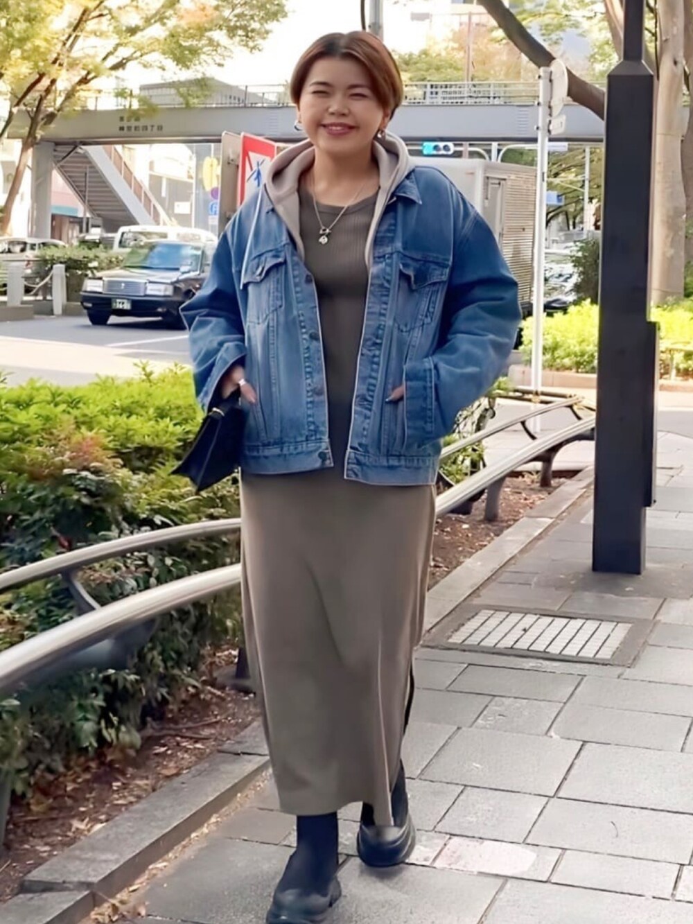 ベージュ系のパーカー、グリーン系のワンピース、ブラック系のハンドバッグを着用したレディースの秋コーディネートの3枚目の写真