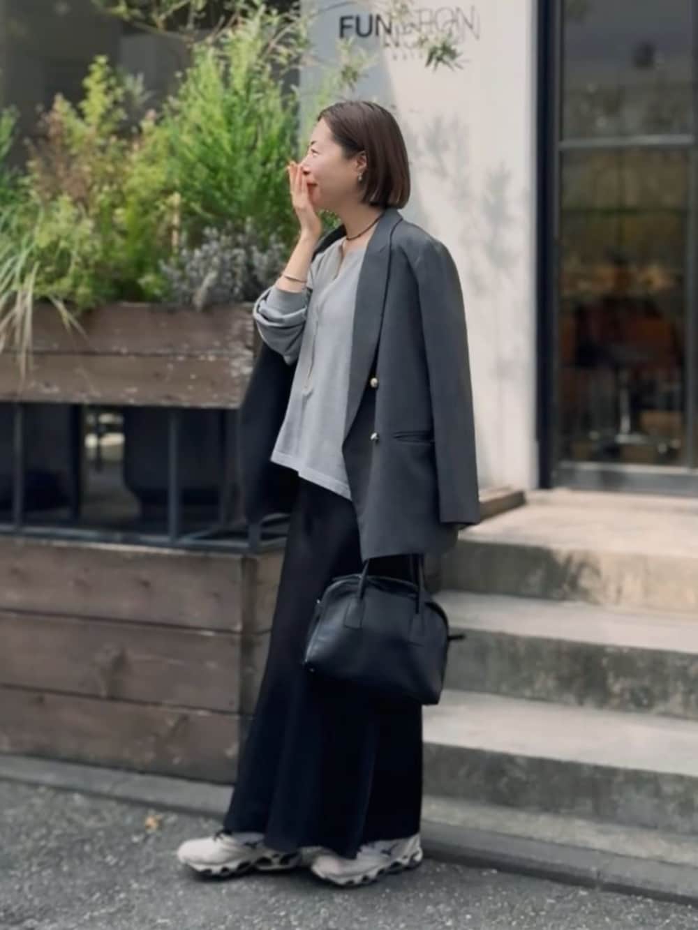 ブラック系のボストンバッグ、ブラック系のスカート、グレー系のテーラードジャケットを着用したレディースの冬コーディネートの5枚目の写真