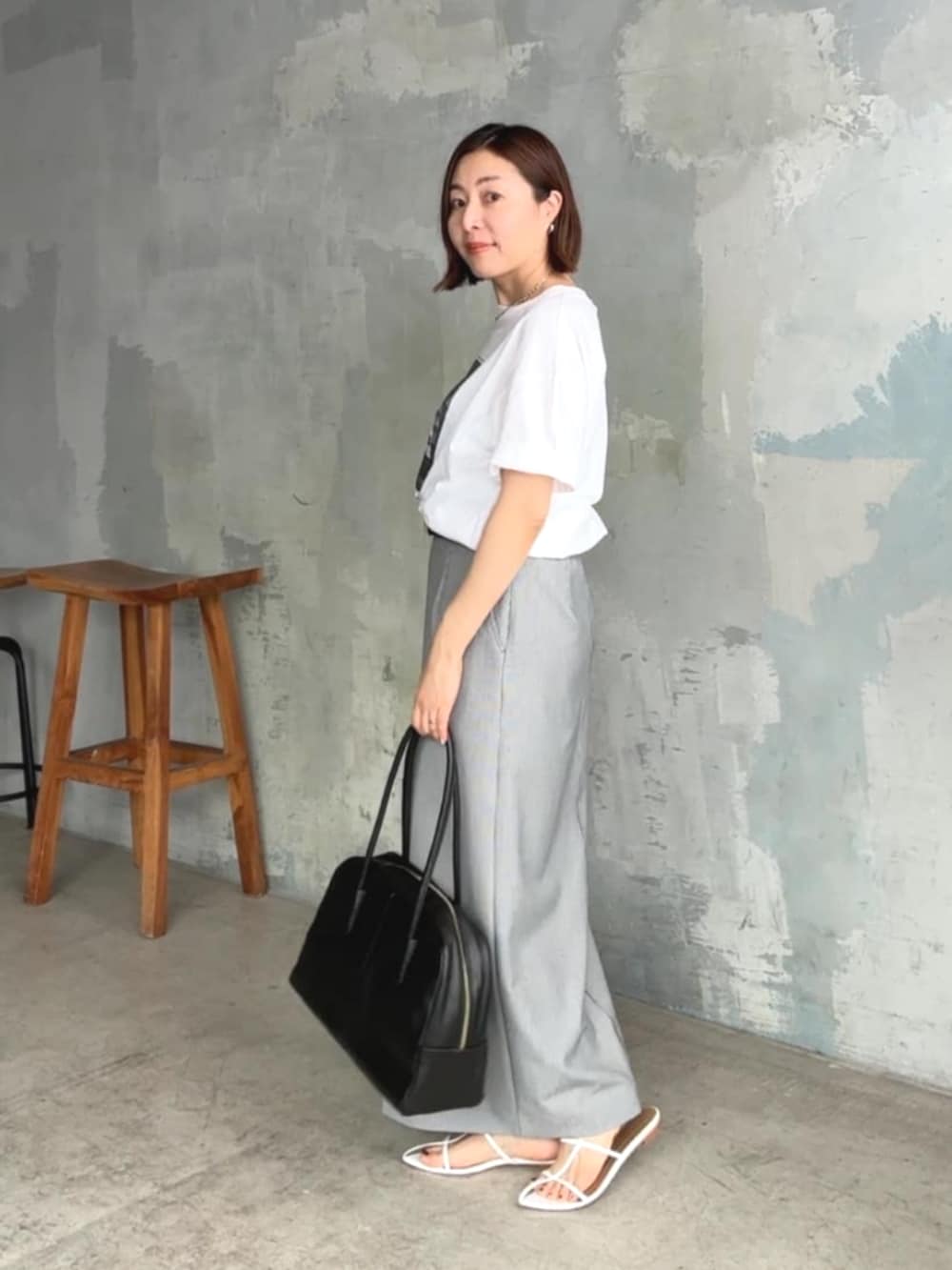 ホワイト系のTシャツ/カットソー、ホワイト系のサンダル、ブラック系のスカートを着用したレディースの夏コーディネートの2枚目の写真