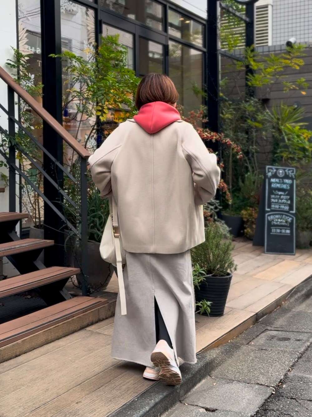 ベージュ系のピーコート、ベージュ系のパーカー、グレー系のデニムスカートを着用したレディースの冬コーディネートの2枚目の写真