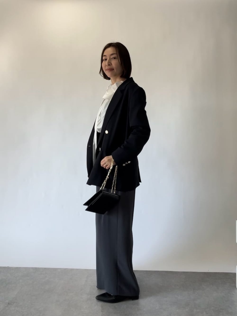 ブルー系のテーラードジャケット、ホワイト系のシャツ/ブラウス、グレー系のスラックスを着用したレディースの冬コーディネートの2枚目の写真