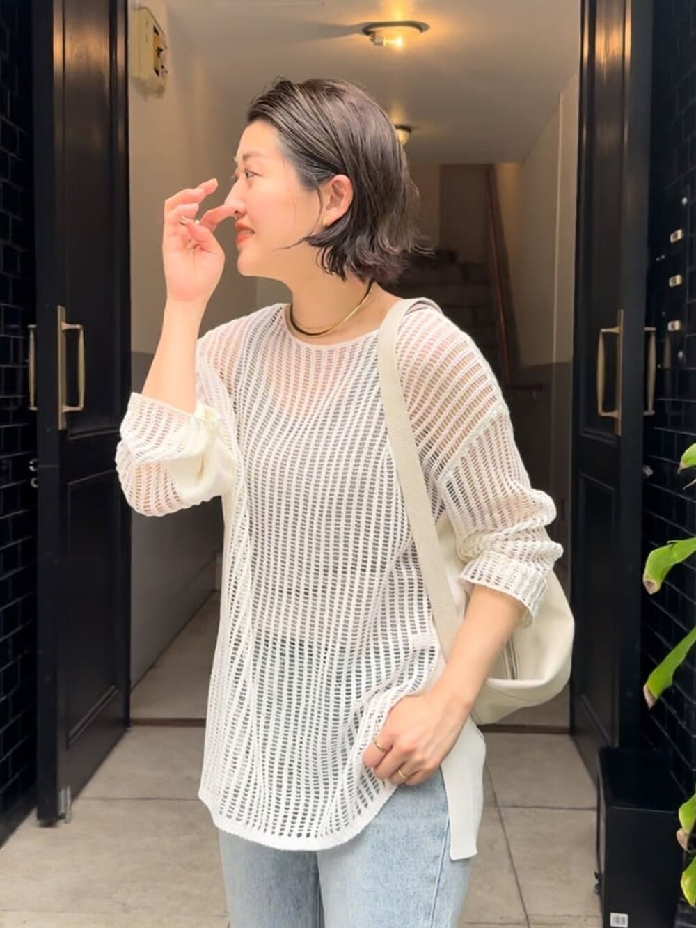 ホワイト系のニット/セーター、ブルー系のデニムパンツ、ホワイト系のボディバッグ/ウエストポーチを着用したレディースの春コーディネートの3枚目の写真