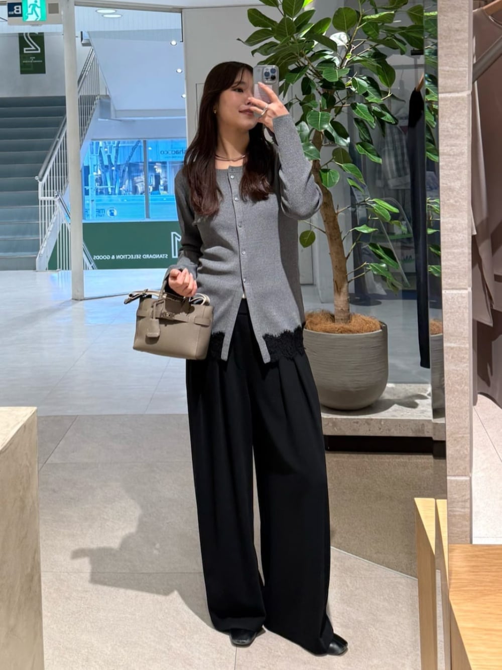 ブラック系のスラックス、グレー系のトートバッグ、グレー系のカーディガン/ボレロを着用したレディースの冬コーディネートの2枚目の写真