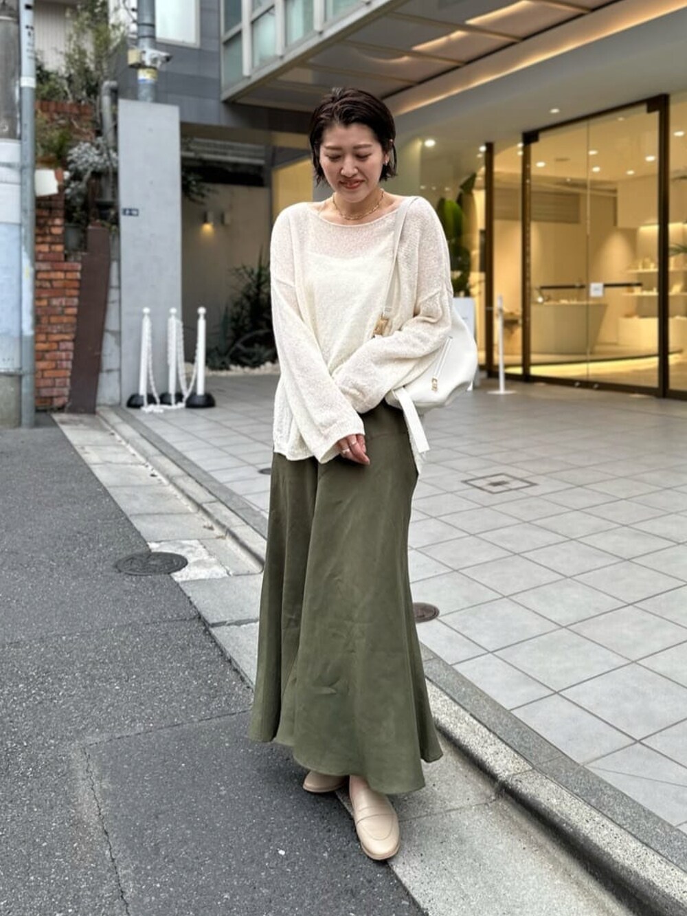 ホワイト系のニット/セーター、ホワイト系のキャミソール、グリーン系のスカートを着用したレディースの春コーディネートの3枚目の写真