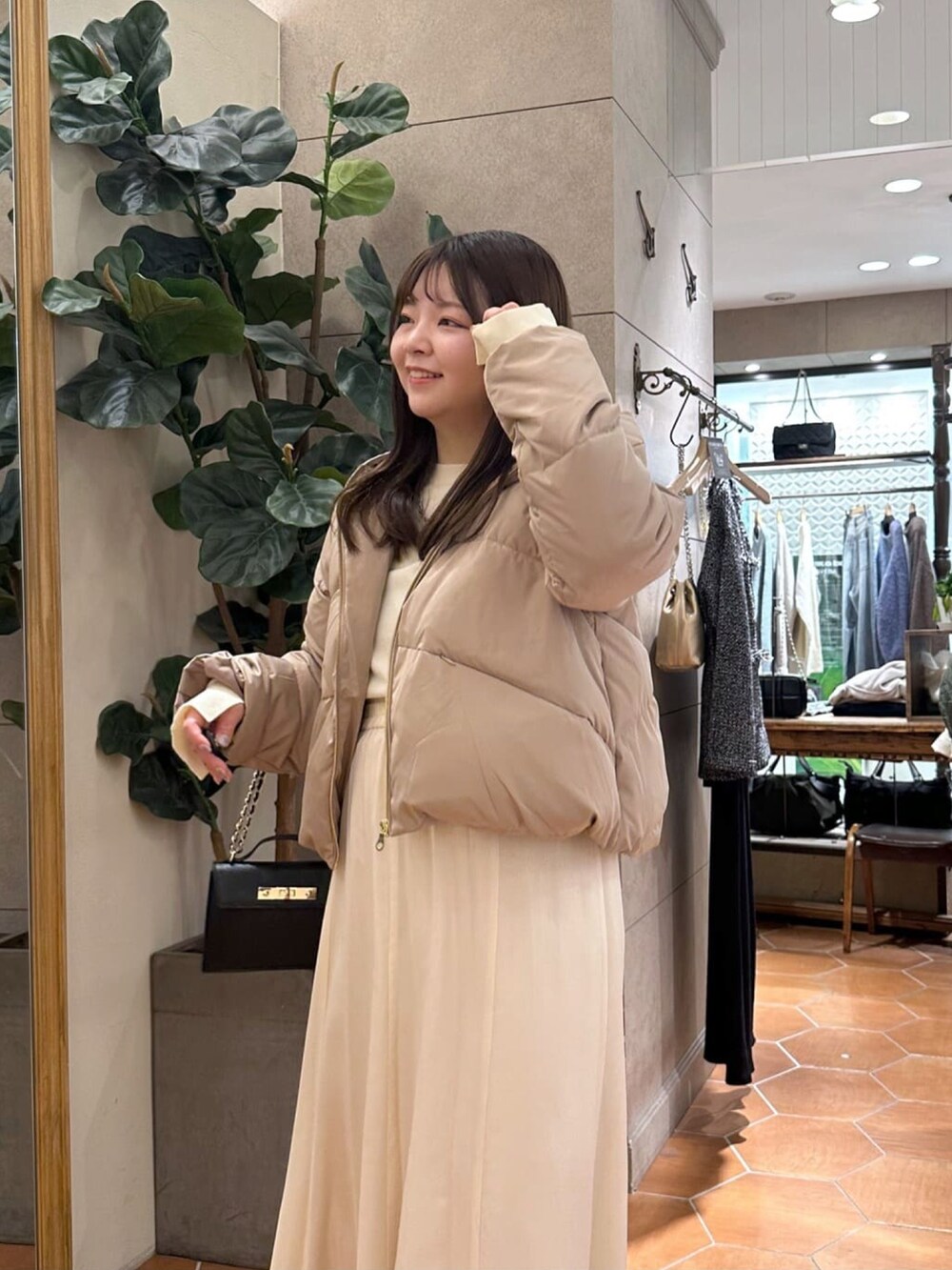 ブラック系のダウンジャケット/コート、ホワイト系のスカート、ブラック系のハンドバッグを着用したレディースの冬コーディネートの4枚目の写真