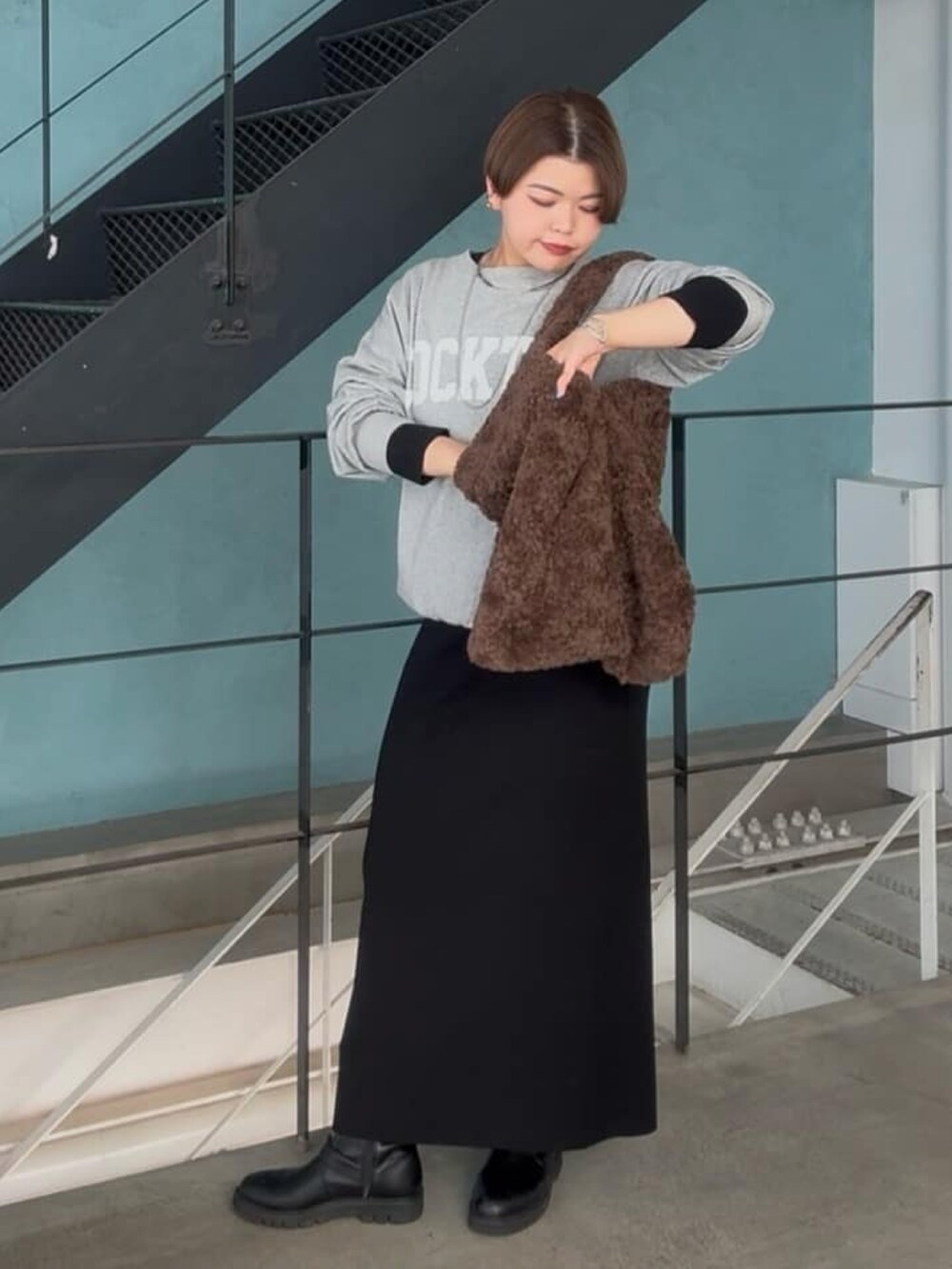 グレー系のスウェット、ブラック系のワンピースを着用したレディースの冬コーディネートの2枚目の写真