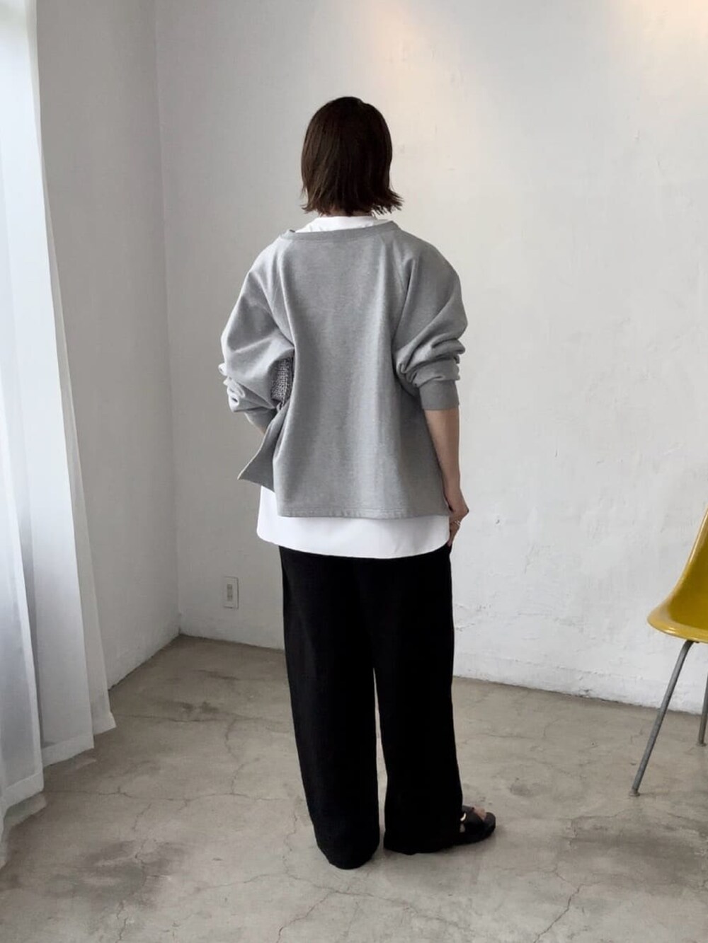 グレー系のスウェット、ブラック系のスラックス、ブラック系のサンダルを着用したレディースの秋コーディネートの3枚目の写真