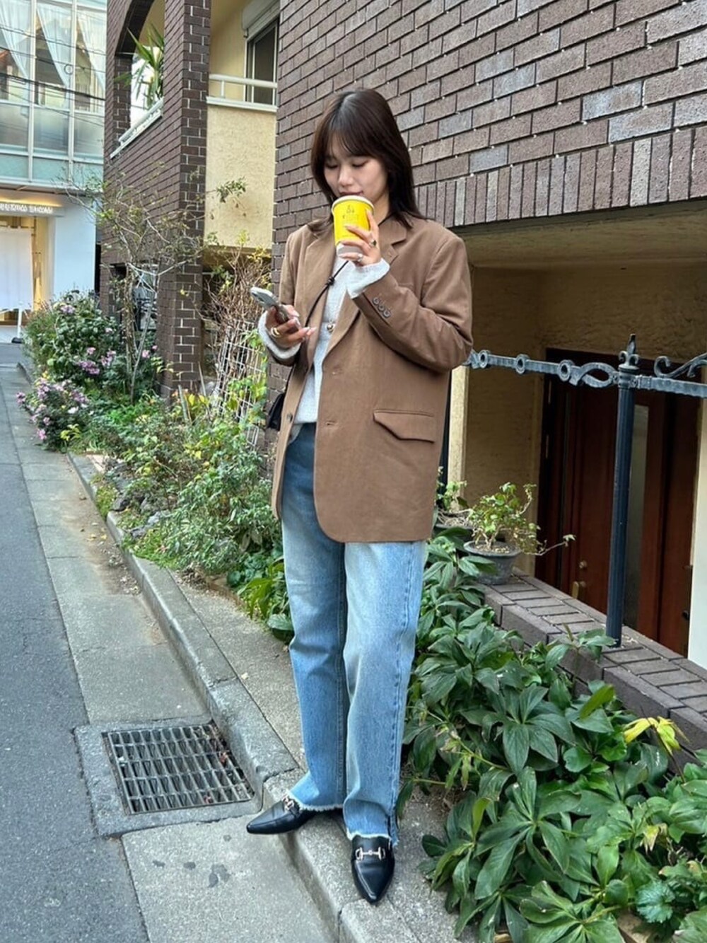 ブラウン系のテーラードジャケット、グレー系のニット/セーター、グレー系のデニムパンツを着用したレディースの冬コーディネートの3枚目の写真