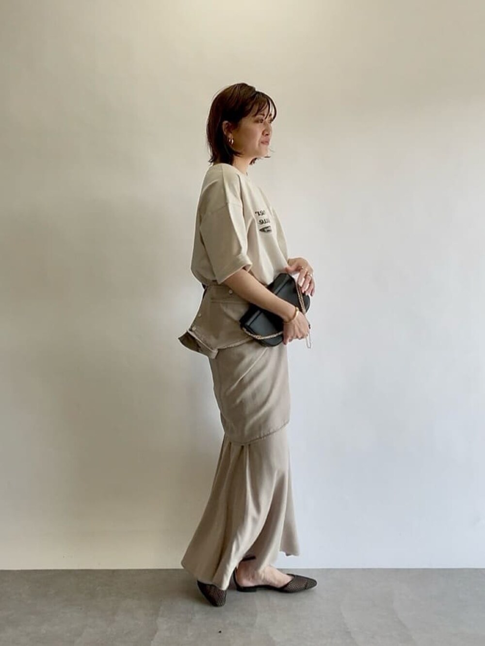 グレー系のスカート、ブラック系のショルダーバッグ、ブラック系のパンプスを着用したレディースの冬コーディネートの3枚目の写真