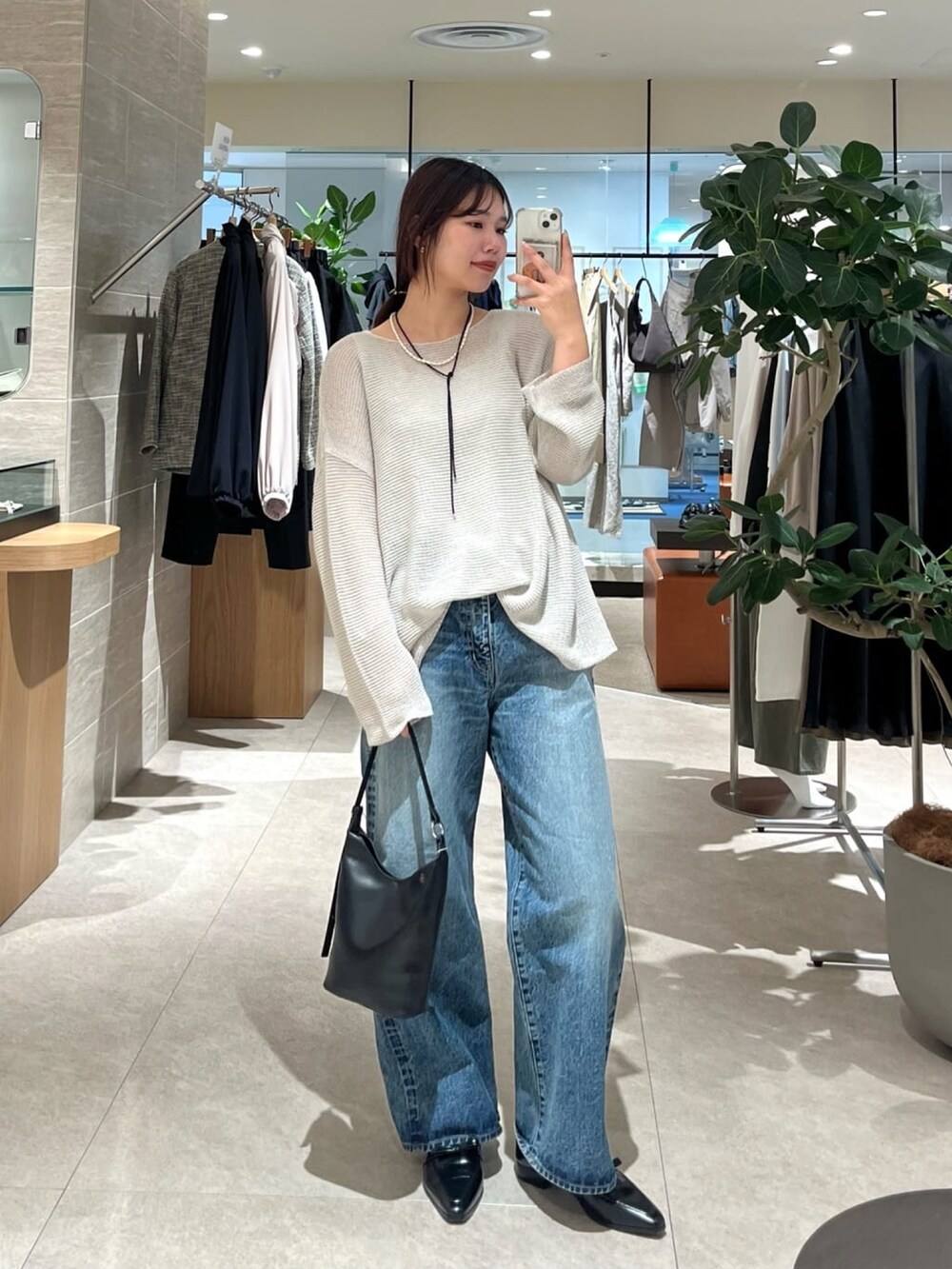 グレー系のニット/セーター、ブルー系のデニムパンツ、ブラック系のハンドバッグを着用したレディースの冬コーディネートの2枚目の写真