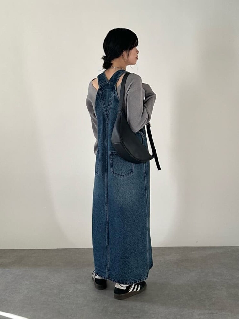 ブルー系のジャンパースカート、グレー系のニット/セーター、ブラック系のボディバッグ/ウエストポーチを着用したレディースの冬コーディネートの3枚目の写真