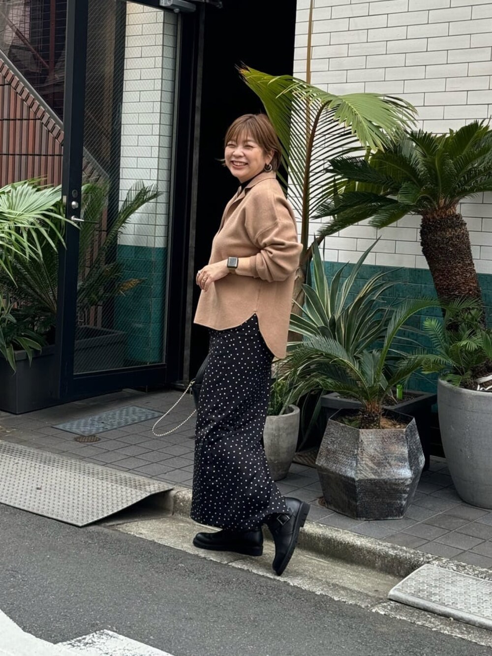 イエロー系のニット/セーター、ブラック系のスカート、ブラック系のブーツを着用したレディースの秋コーディネートの3枚目の写真