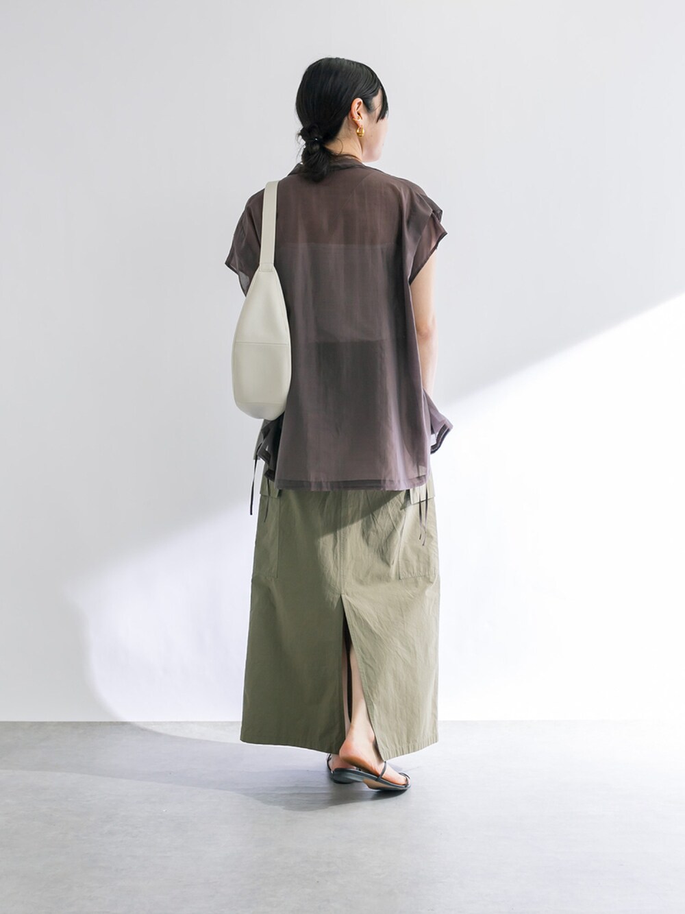 グリーン系のスカート、ホワイト系のキャミソール、ブラック系のサンダルを着用したレディースの春コーディネートの3枚目の写真