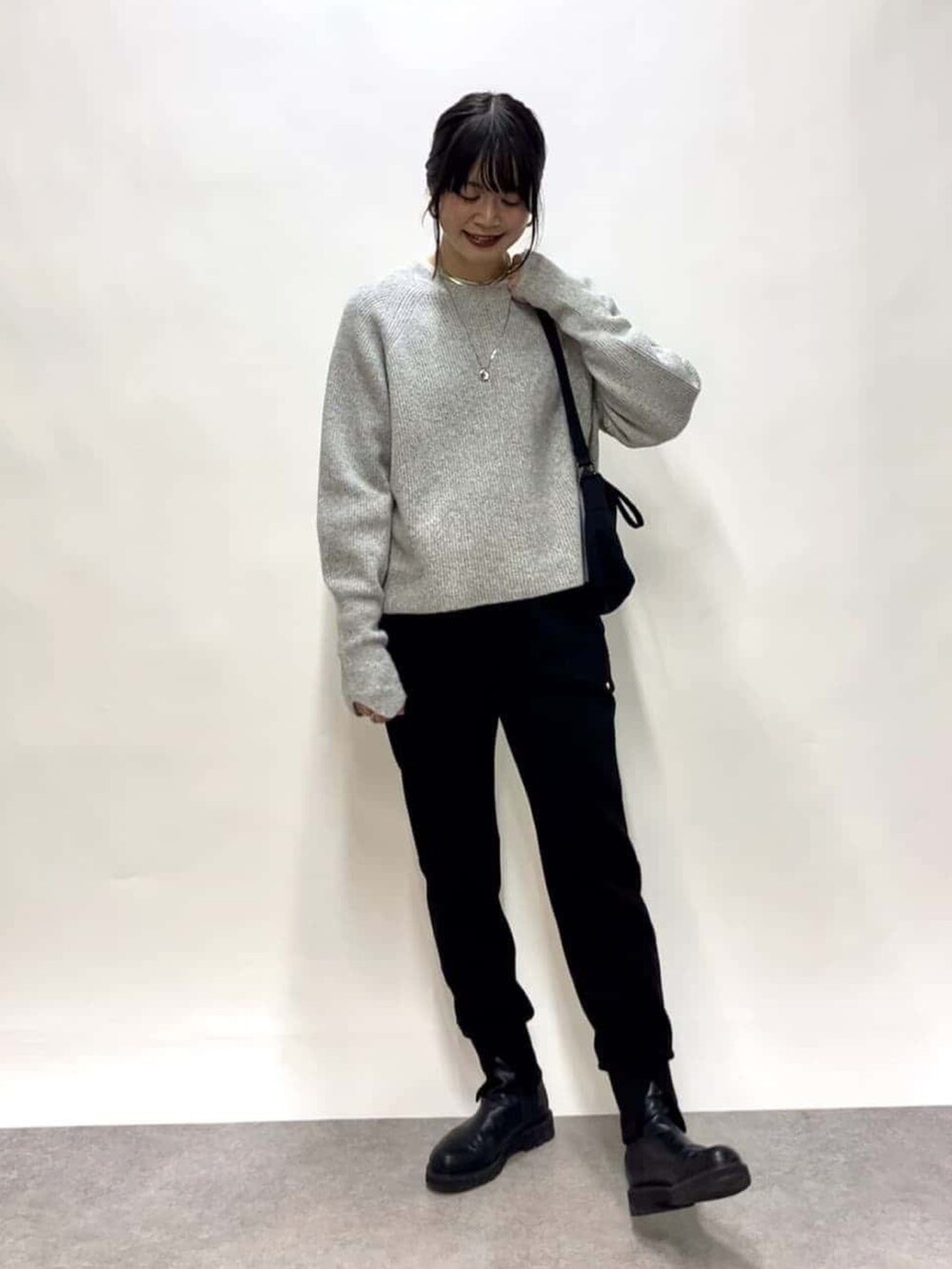 ブラック系のスウェットパンツ、ブラック系のブーツ、グレー系のニット/セーターを着用したレディースの冬コーディネートの3枚目の写真