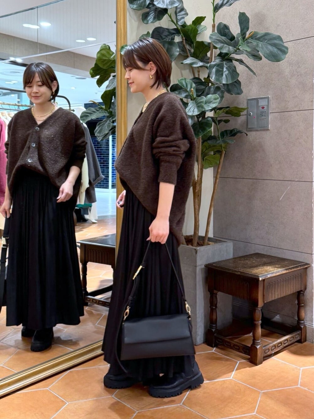 ブラウン系のカーディガン/ボレロ、ブラック系のスカート、ブラック系のショルダーバッグを着用したレディースの冬コーディネートの2枚目の写真