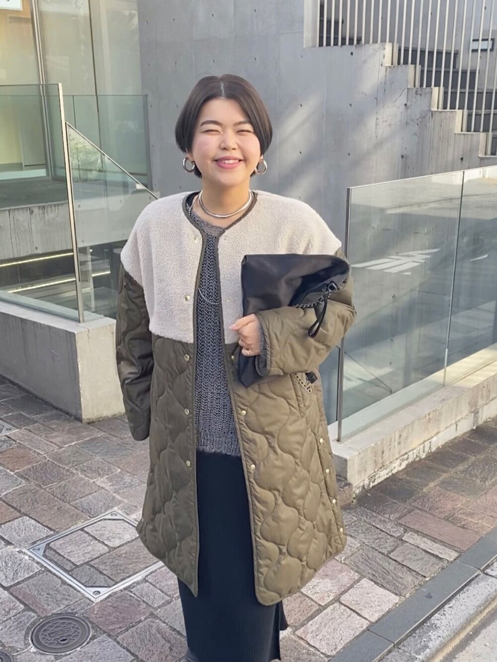 グリーン系のダウンジャケット/コート、グレー系のワンピース、ブラック系のブーツを着用したレディースの冬コーディネートの3枚目の写真