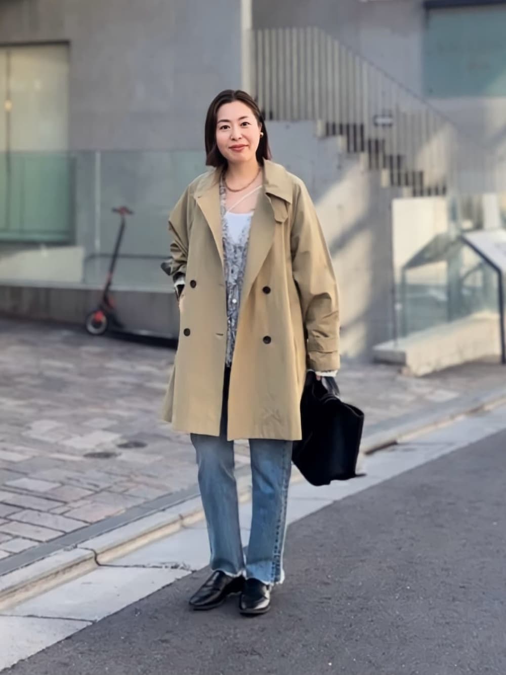 ベージュ系のトレンチコート、ブルー系のデニムパンツ、ブラック系のローファーを着用したレディースの冬コーディネートの2枚目の写真