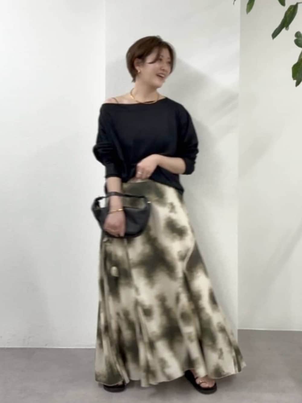 ブラック系のショルダーバッグ、ベージュ系のスカート、ブラック系のサンダルを着用したレディースの春コーディネートの3枚目の写真