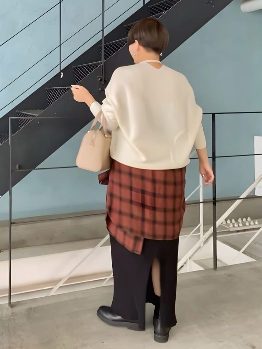 ホワイト系のニット/セーター、ベージュ系のボストンバッグ、ブラック系のスカートを着用したレディースの冬コーディネートの2枚目の写真